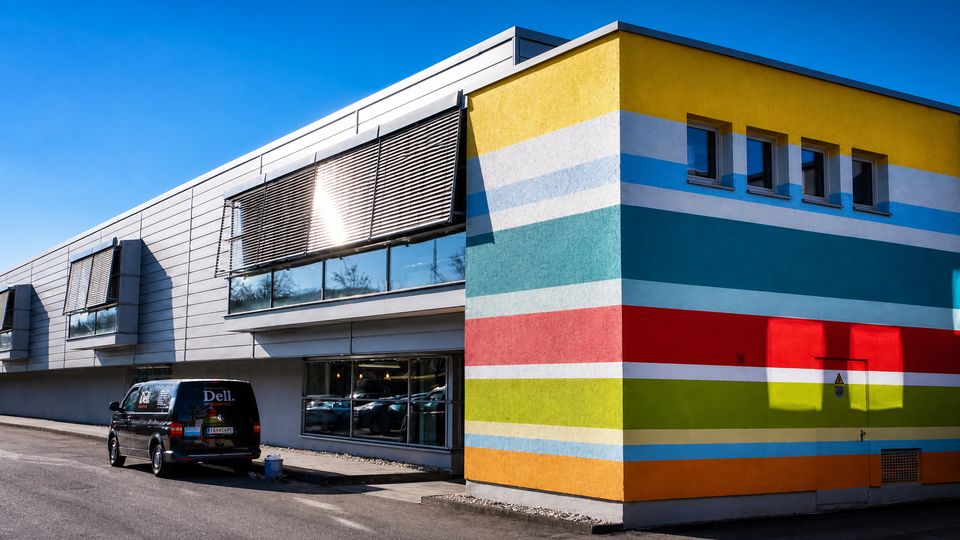 Bunt gestreifte Fassade eines Gewerbegeb&auml;udes mit Firmenfahrzeug davor