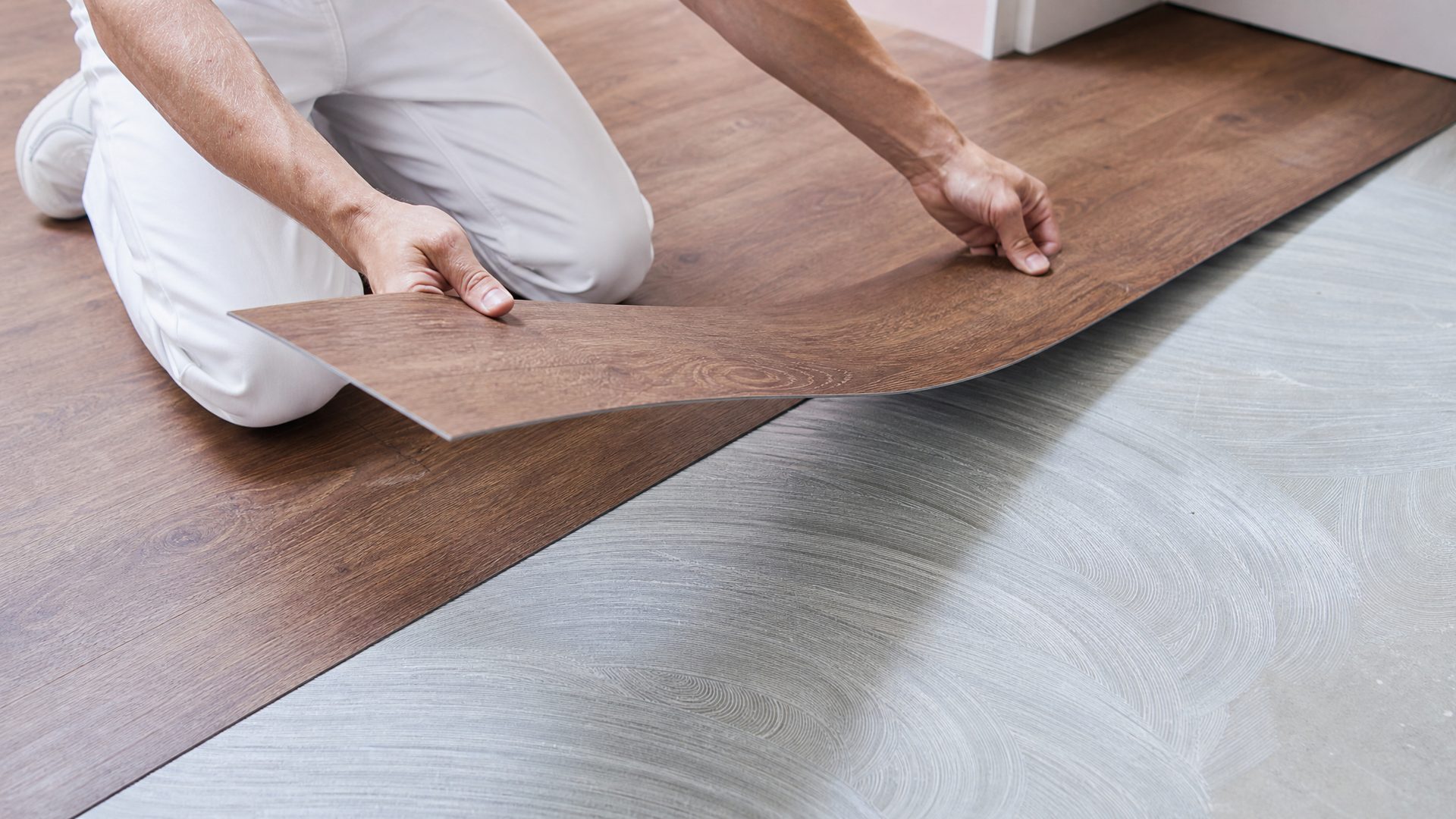Handwerker verlegt einen holzoptik Vinyl-Bodenbelag auf dem Unterboden