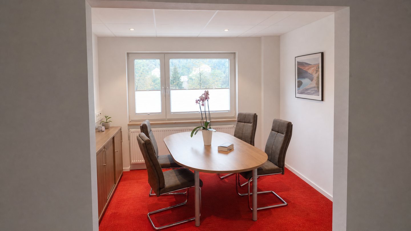 Besprechungsraum nach der Renovierung, abgeh&auml;ngte Decke, roter Teppichboden und ovaler Besprechungstisch
